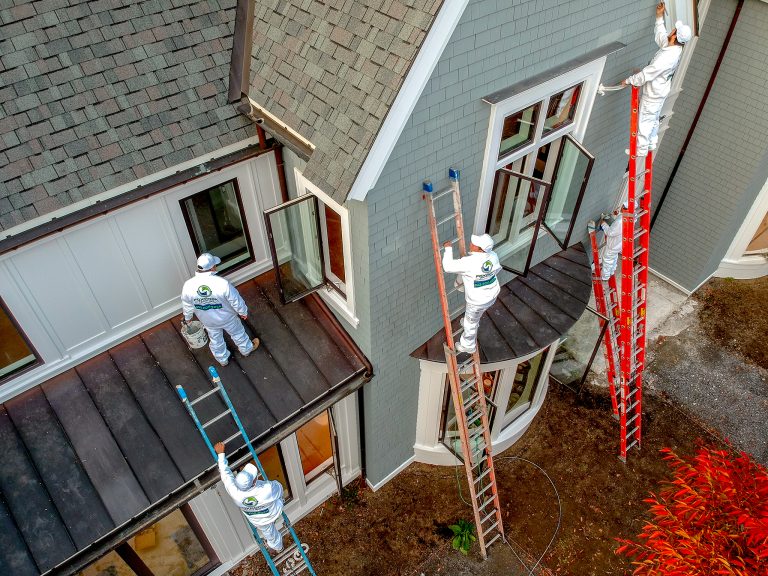 workers on ladder painting large home